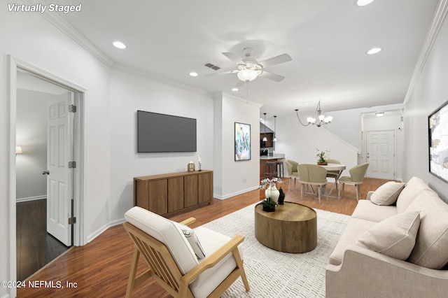 living room with ornamental molding, ceiling fan with notable chandelier, and dark hardwood / wood-style flooring