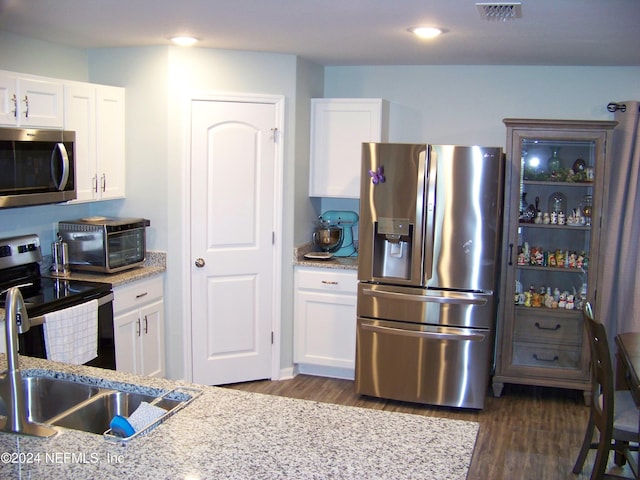 kitchen featuring light stone countertops, stainless steel appliances, white cabinets, dark wood-type flooring, and sink