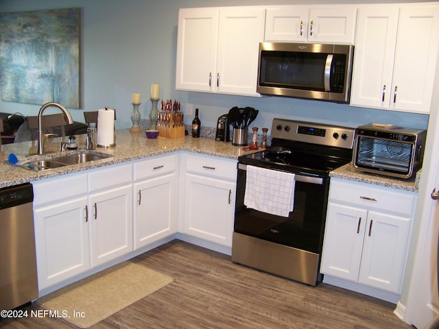 kitchen featuring white cabinets, sink, stainless steel appliances, dark hardwood / wood-style floors, and light stone countertops