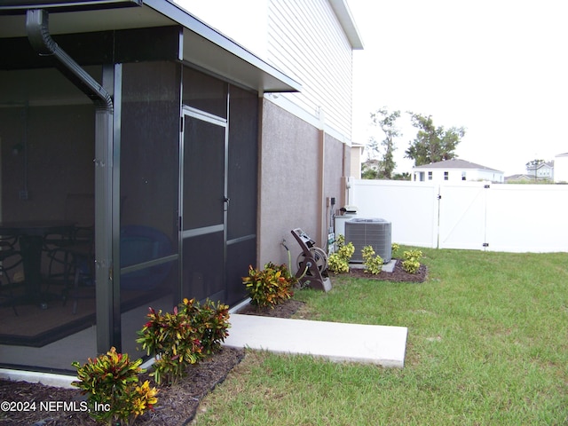 view of property exterior with a sunroom, a lawn, and central AC