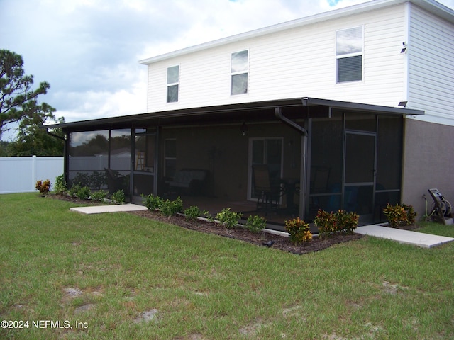 rear view of house with a sunroom and a lawn