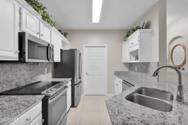 kitchen with sink, backsplash, stainless steel appliances, white cabinets, and light stone counters