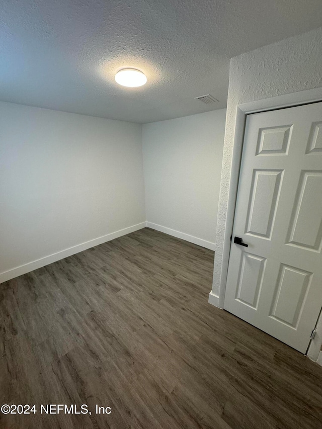 empty room featuring dark hardwood / wood-style flooring and a textured ceiling