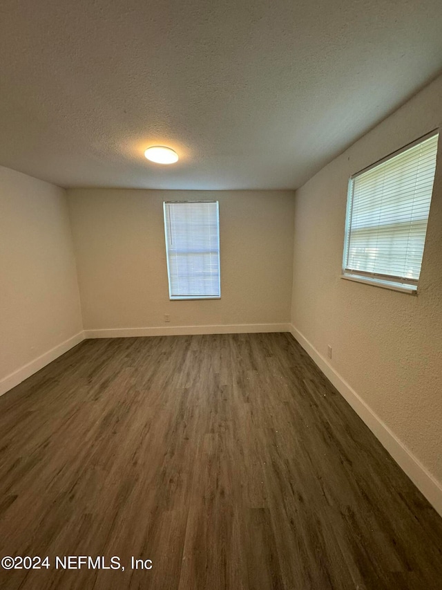 unfurnished room with a textured ceiling and dark hardwood / wood-style flooring