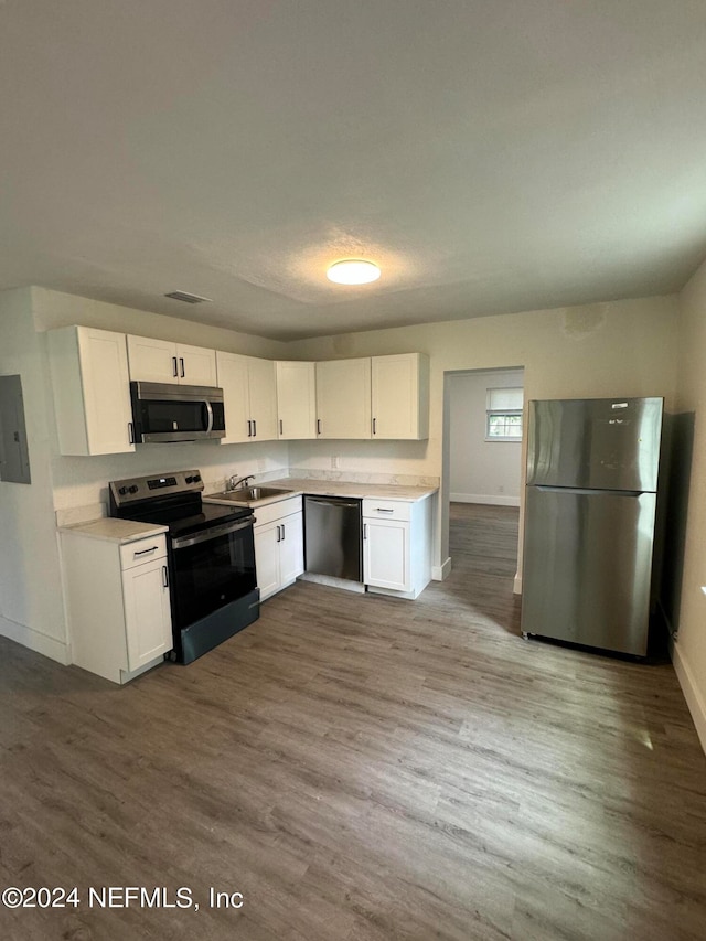 kitchen featuring white cabinets, hardwood / wood-style flooring, sink, and appliances with stainless steel finishes