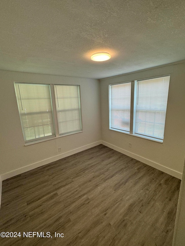 spare room with a textured ceiling and dark hardwood / wood-style flooring