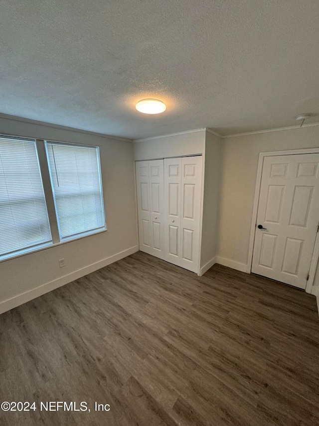 unfurnished bedroom featuring a textured ceiling, dark hardwood / wood-style floors, and a closet