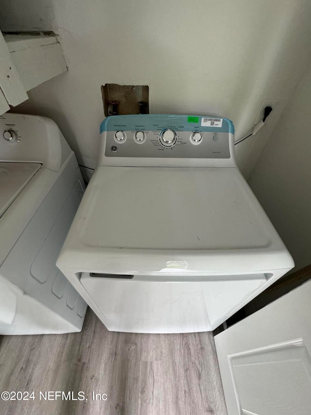 washroom featuring wood-type flooring and separate washer and dryer