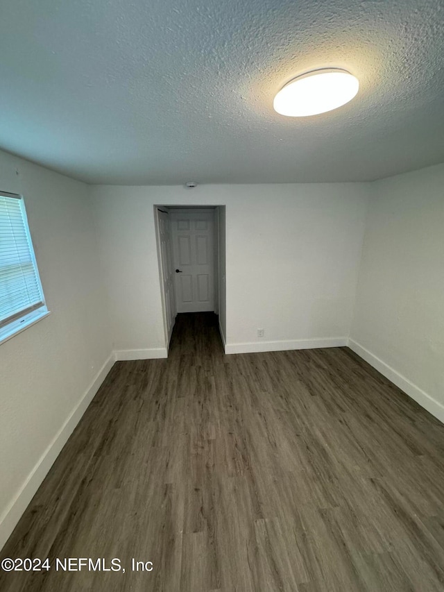 spare room with a textured ceiling and dark hardwood / wood-style floors