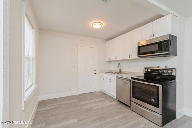 kitchen featuring stainless steel appliances, white cabinetry, light hardwood / wood-style floors, and sink