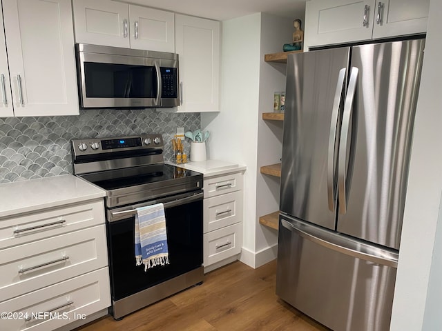 kitchen with tasteful backsplash, white cabinetry, hardwood / wood-style floors, and appliances with stainless steel finishes