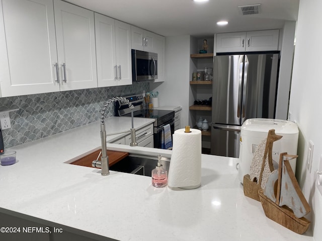 kitchen featuring kitchen peninsula, appliances with stainless steel finishes, tasteful backsplash, and sink