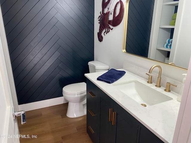 bathroom with wood-type flooring, vanity, toilet, and wood walls