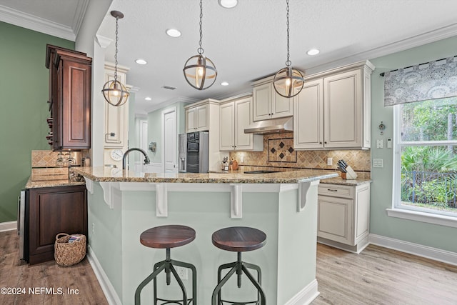 kitchen with light stone counters, a breakfast bar area, light hardwood / wood-style flooring, and hanging light fixtures