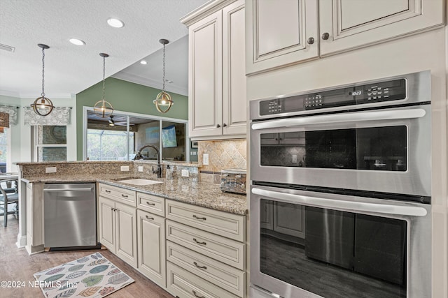 kitchen featuring light stone countertops, sink, stainless steel appliances, and ornamental molding