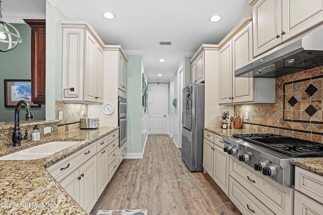 kitchen with decorative backsplash, stainless steel appliances, sink, light hardwood / wood-style floors, and pendant lighting