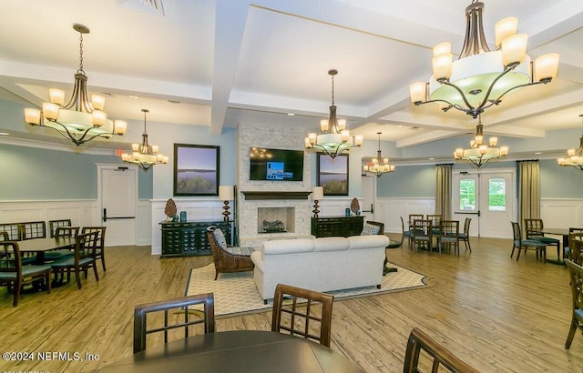 living room featuring coffered ceiling, light wood-type flooring, beam ceiling, and a stone fireplace