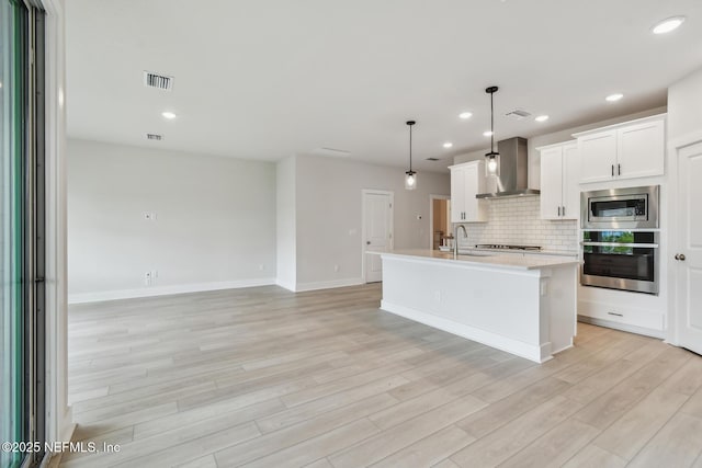 10266 Element Rd, Jacksonville, FL 32256 - kitchen featuring stainless steel appliances, wall chimney exhaust hood, a sink, light wood-style flooring, and light countertops