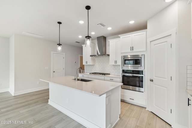 10266 Element Rd, Jacksonville, FL 32256 - kitchen featuring appliances with stainless steel finishes, wall chimney exhaust hood, a sink, light wood-type flooring, and decorative backsplash