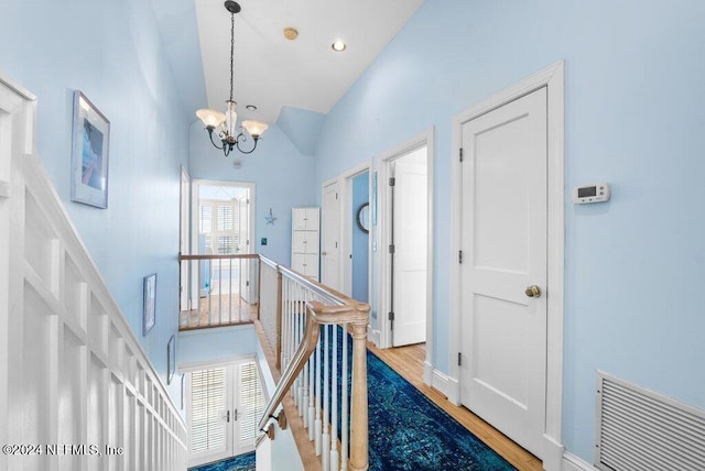 hallway featuring a chandelier, hardwood / wood-style floors, and high vaulted ceiling