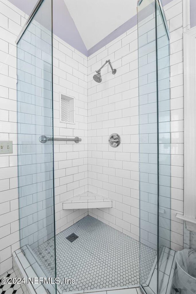 bathroom with tile patterned floors, lofted ceiling, and tiled shower