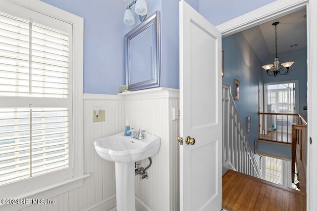 bathroom with an inviting chandelier, a healthy amount of sunlight, and hardwood / wood-style flooring