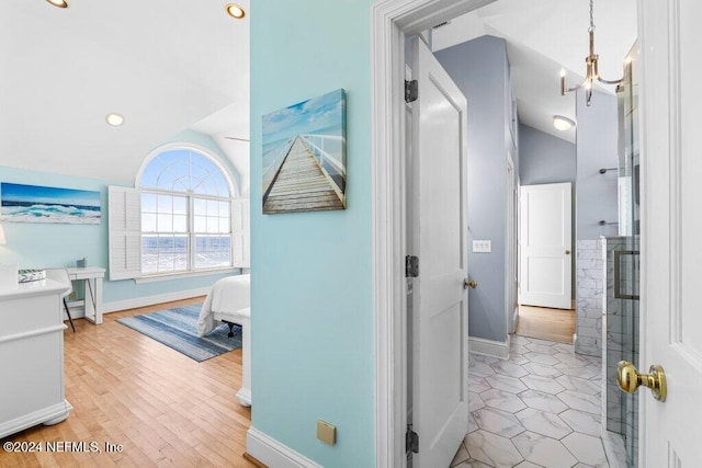 hallway featuring a chandelier, light hardwood / wood-style floors, and vaulted ceiling