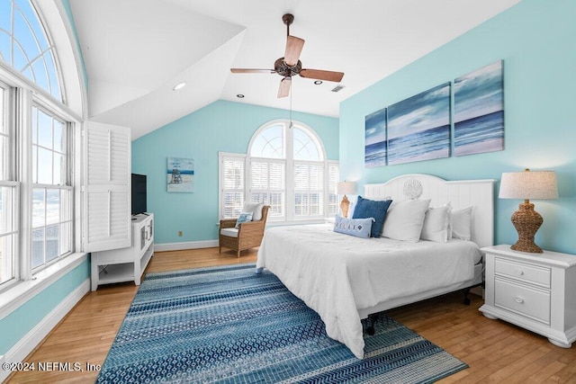 bedroom with multiple windows, ceiling fan, vaulted ceiling, and light wood-type flooring