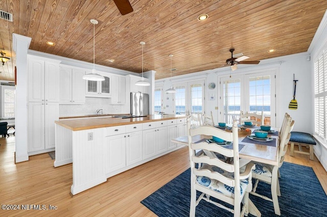 kitchen with a healthy amount of sunlight, white cabinets, wooden counters, and a kitchen island