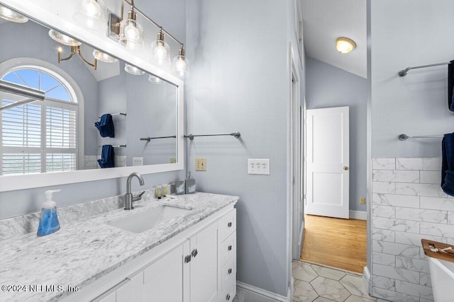 bathroom with wood-type flooring, vanity, and lofted ceiling