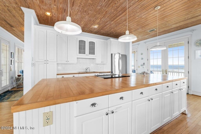 kitchen with wood counters, stainless steel fridge, a center island, and white cabinetry