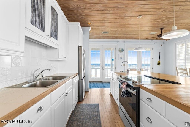 kitchen with white cabinets, decorative light fixtures, light wood-type flooring, and french doors