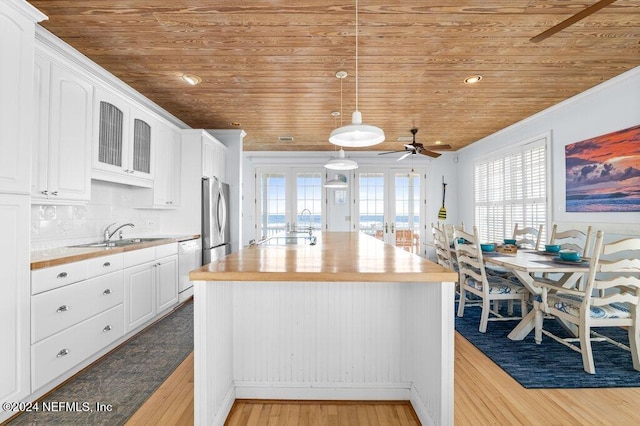 kitchen featuring butcher block counters, white cabinetry, french doors, sink, and light hardwood / wood-style flooring