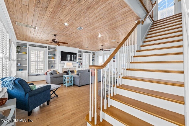 stairway featuring wood-type flooring, built in shelves, wooden ceiling, and ceiling fan