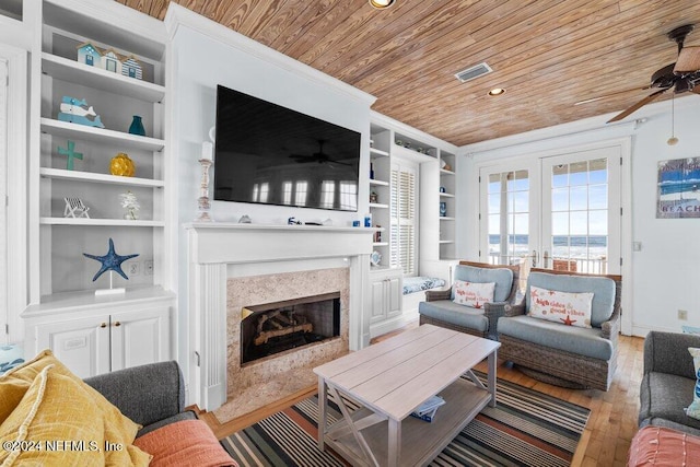 living room featuring a high end fireplace, french doors, built in shelves, light hardwood / wood-style floors, and wood ceiling