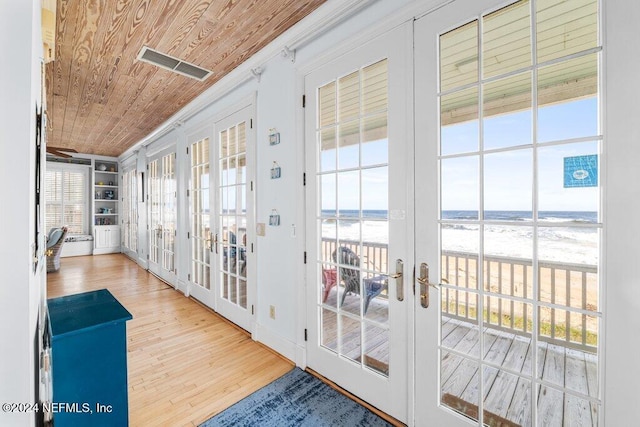 entryway with french doors, a water view, built in features, light hardwood / wood-style flooring, and wooden ceiling