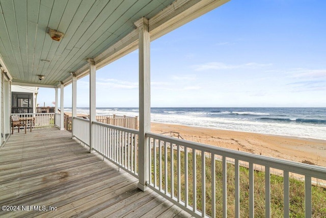 wooden deck with a view of the beach and a water view