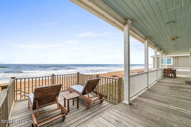 wooden deck with a beach view and a water view