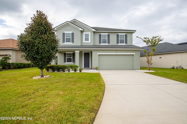 view of property with a garage and a front lawn