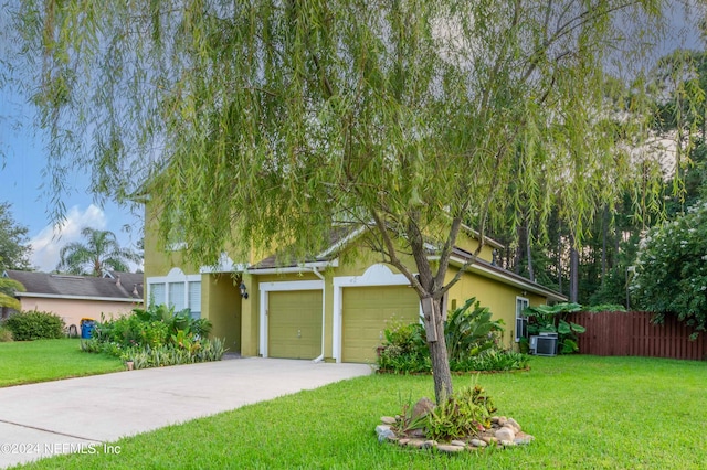 view of property hidden behind natural elements featuring a front lawn and a garage