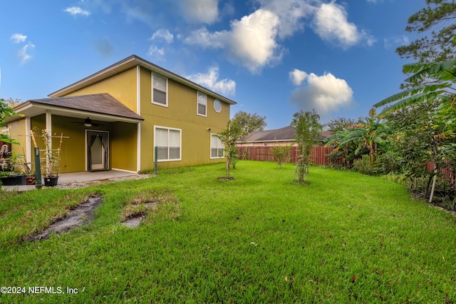 rear view of property featuring a patio, a lawn, and ceiling fan