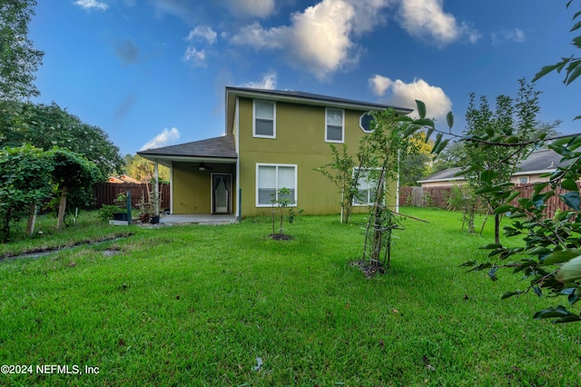 back of house featuring a lawn and a patio area