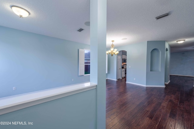 unfurnished room featuring a textured ceiling and dark hardwood / wood-style flooring