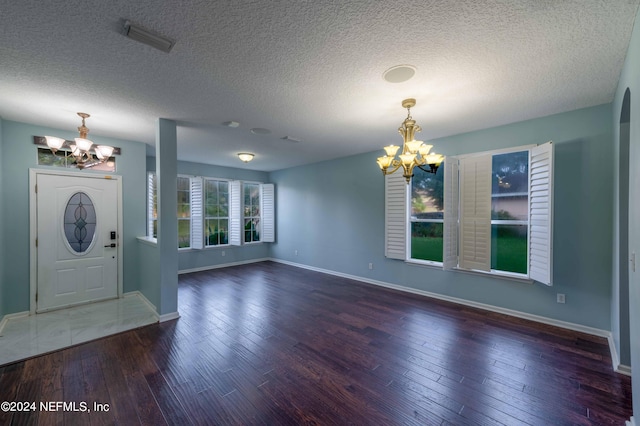 foyer with an inviting chandelier, dark hardwood / wood-style floors, and a textured ceiling