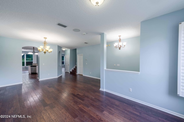 unfurnished room with an inviting chandelier, dark hardwood / wood-style flooring, and a textured ceiling