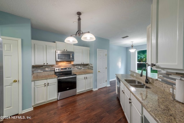 kitchen featuring decorative light fixtures, stainless steel appliances, sink, and white cabinetry