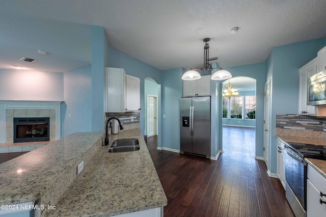 kitchen featuring stainless steel appliances, tasteful backsplash, white cabinets, sink, and pendant lighting