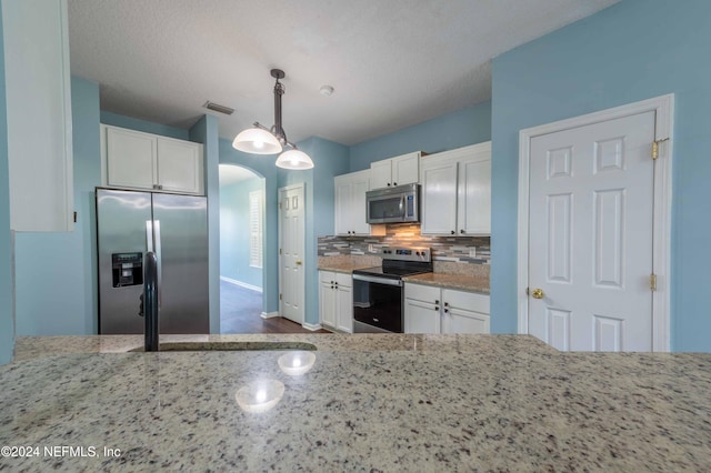 kitchen featuring decorative light fixtures, appliances with stainless steel finishes, light stone counters, and white cabinetry