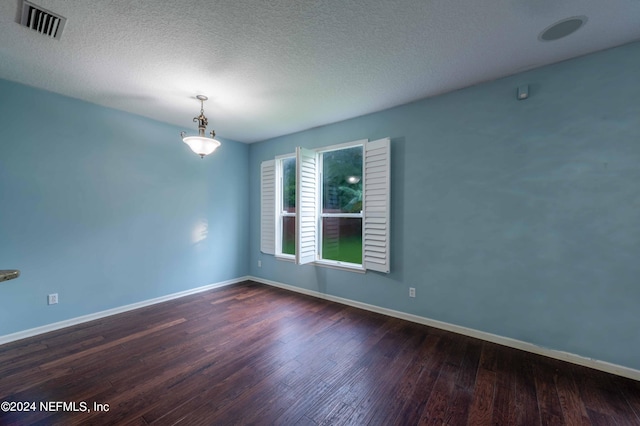 empty room featuring dark wood-type flooring and a textured ceiling