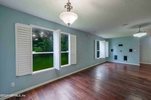 unfurnished room with a textured ceiling and dark hardwood / wood-style flooring